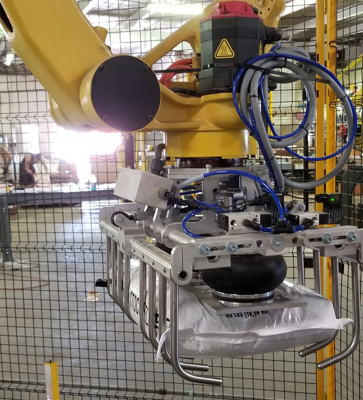 fanuc robot with tool picking up 40 pound bag of livestock feed
