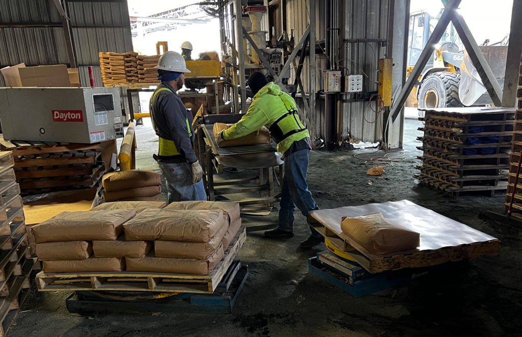 stacking 50 pound bags of abrasive sand on shipping pallets