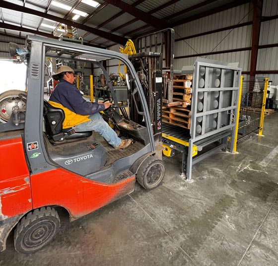 Fork truck operator loading more pallets into dispenser