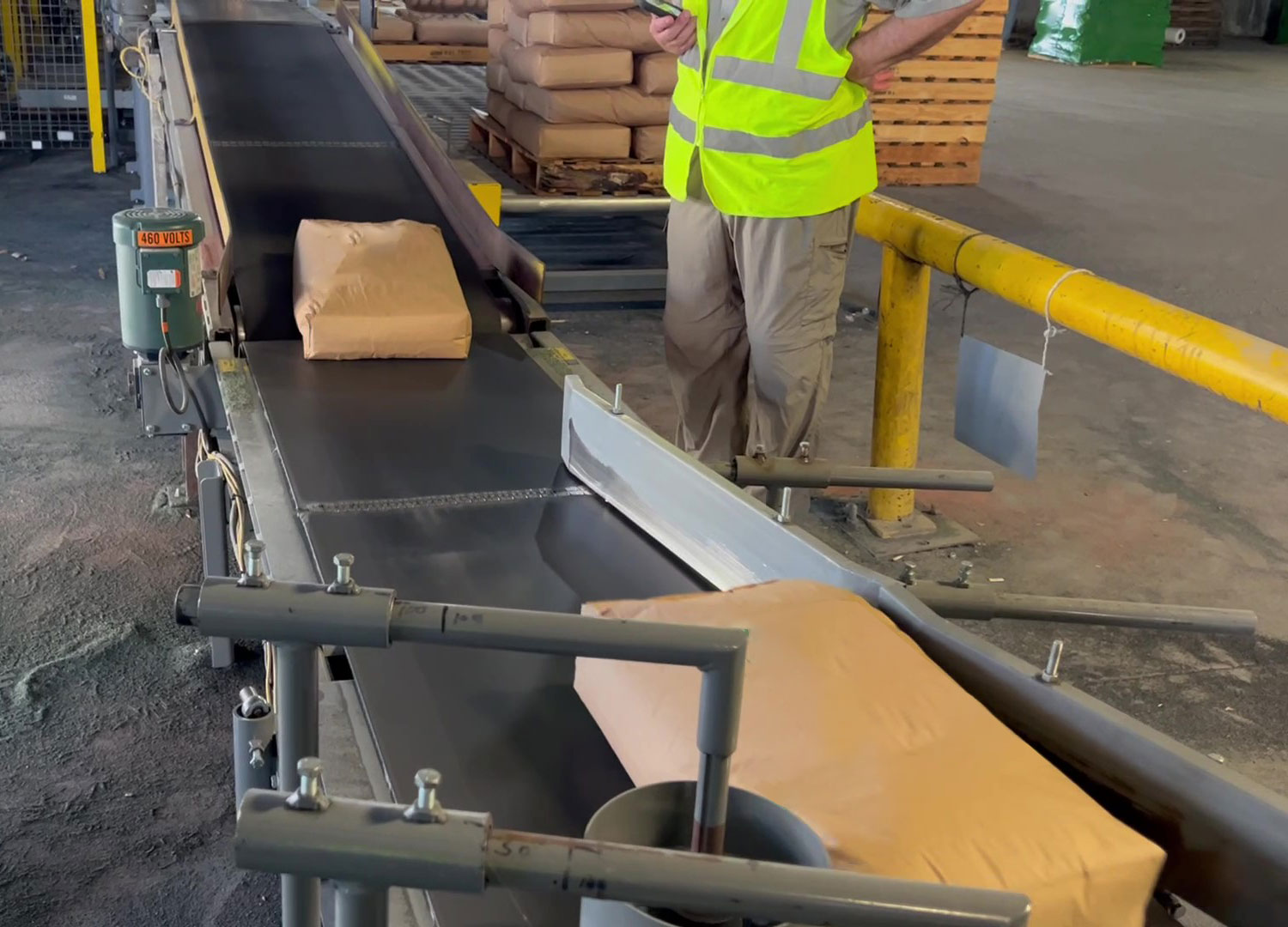 100 lb. bags of minerals moving through bag turning conveyor and up incline conveyor