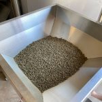Stainless steel hopper filled with mini feed pellets