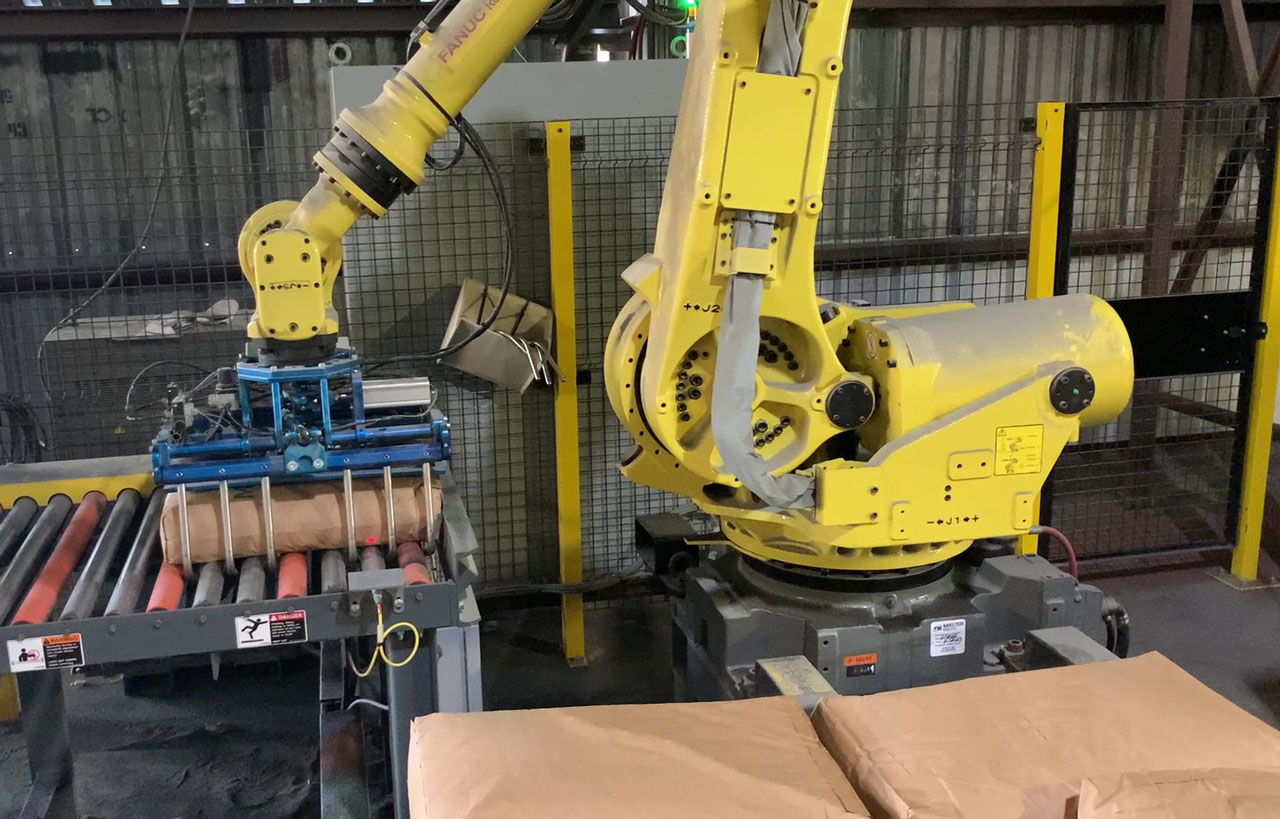 fanuc robot picking up 100 lb. bag of minerals using a bag gripper tool