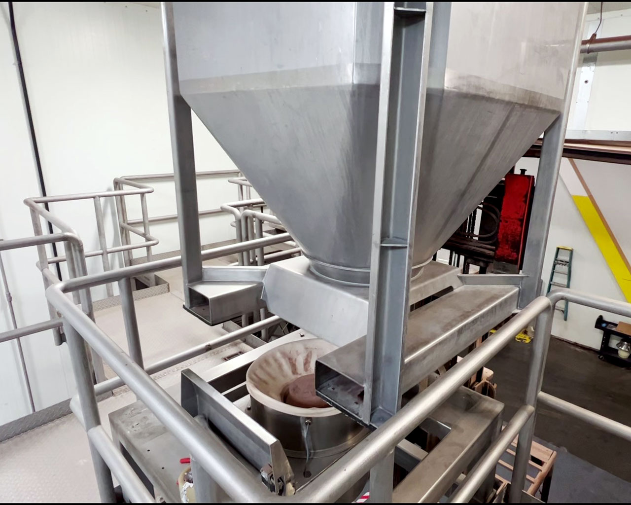 lowering stainless steel IBC bin onto discharge station above powder packaging machine