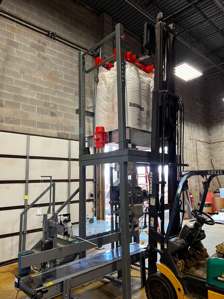 lifting a bulk bag super sack into the unloading station that feeds open mouth bagging machine