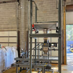 bulk bag unloading system repackages water filter media into open mouth bags
