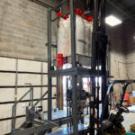 lifting a bulk bag super sack into the unloading station that feeds open mouth bagging machine