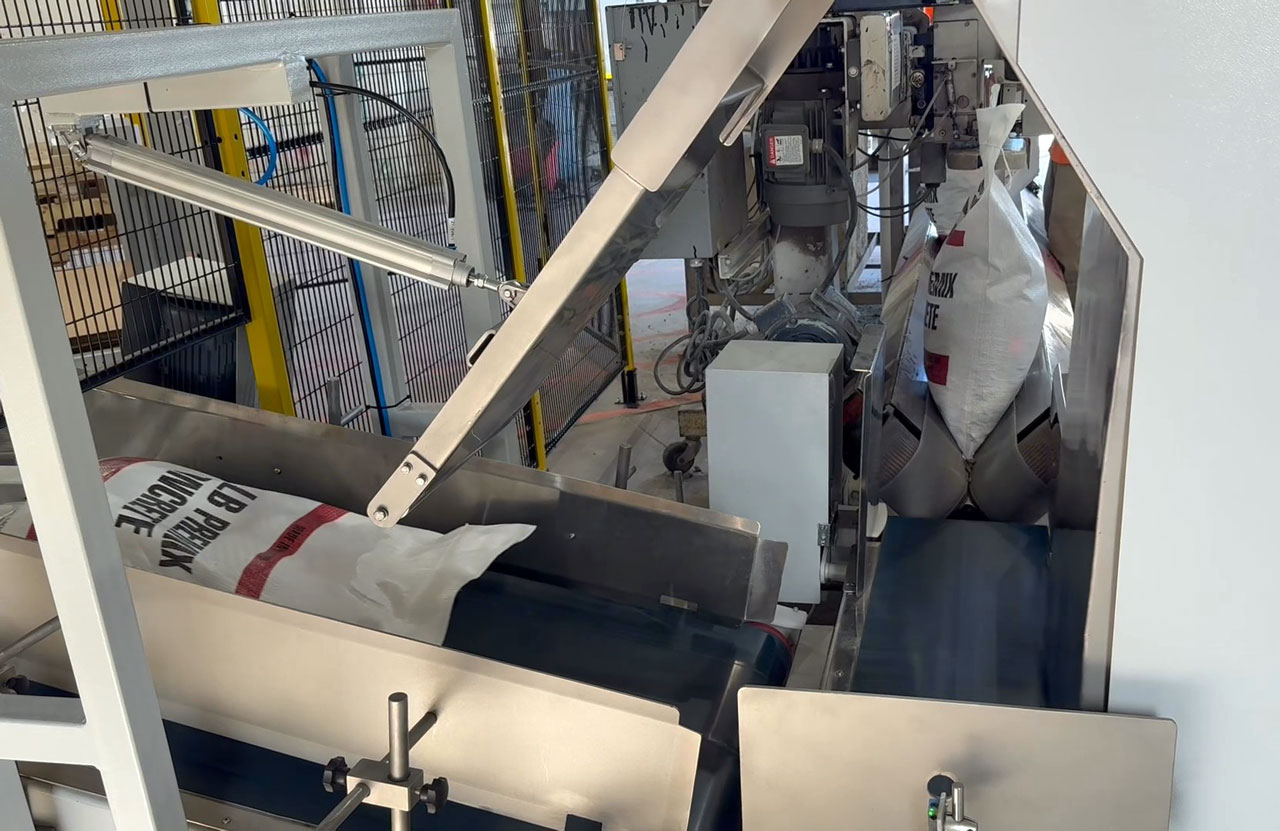 80 lb bag of premix concrete moving from bag sewing system into bag kicker conveyor