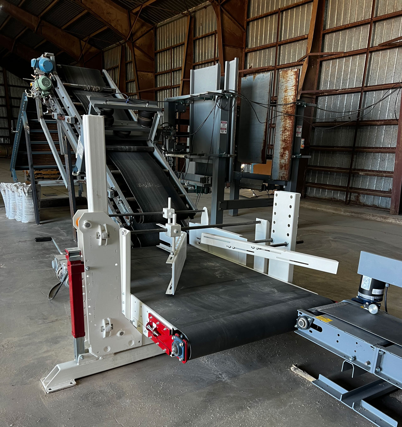 bag tip and turn conveyor and inclined bag flattener conveyor